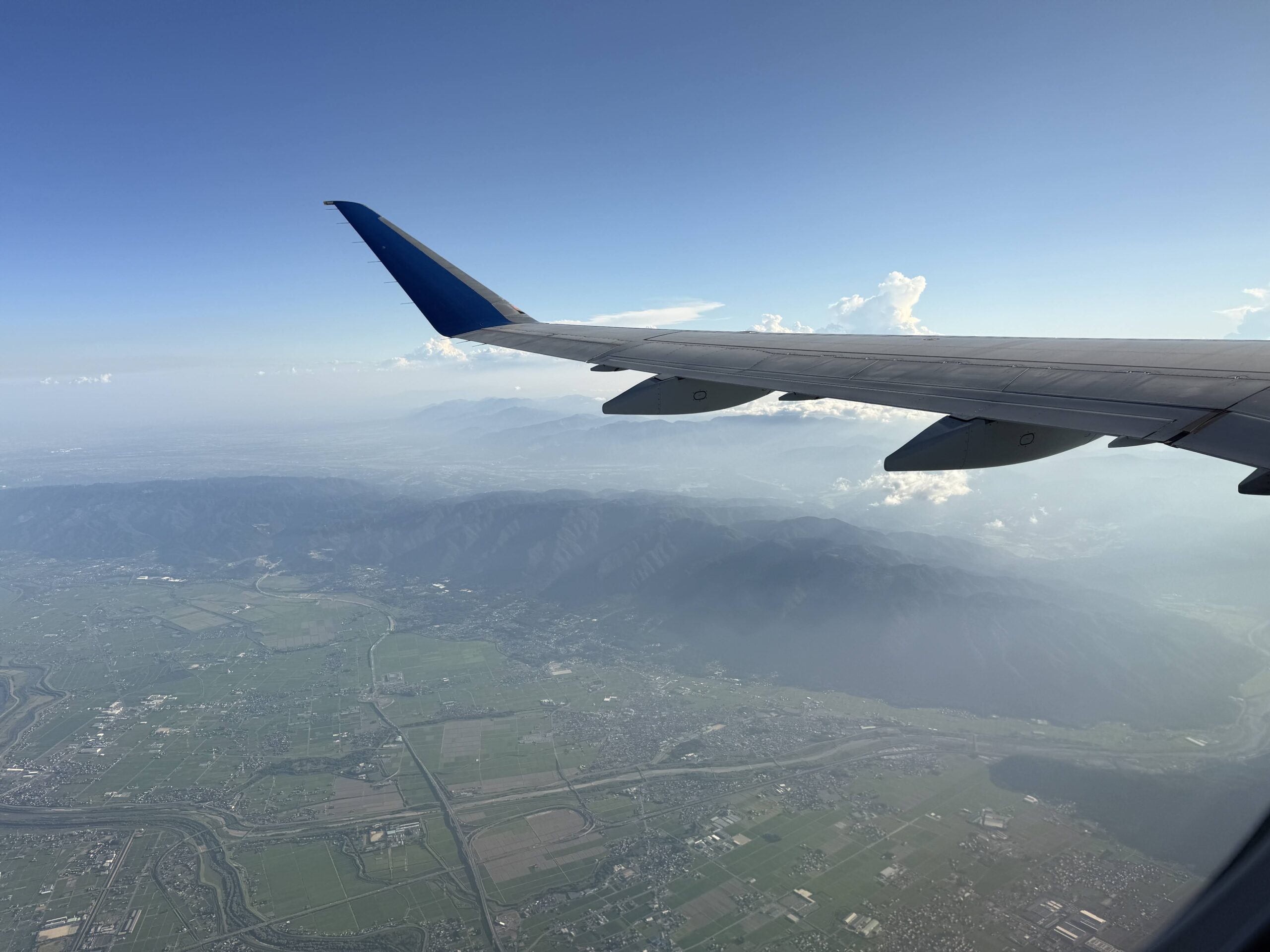 機内窓越しに見える主翼と地上の景色
